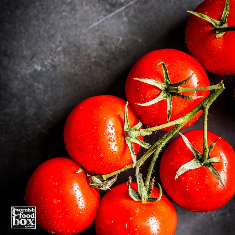 organic cherry tomatoes on the vine on a black slate background