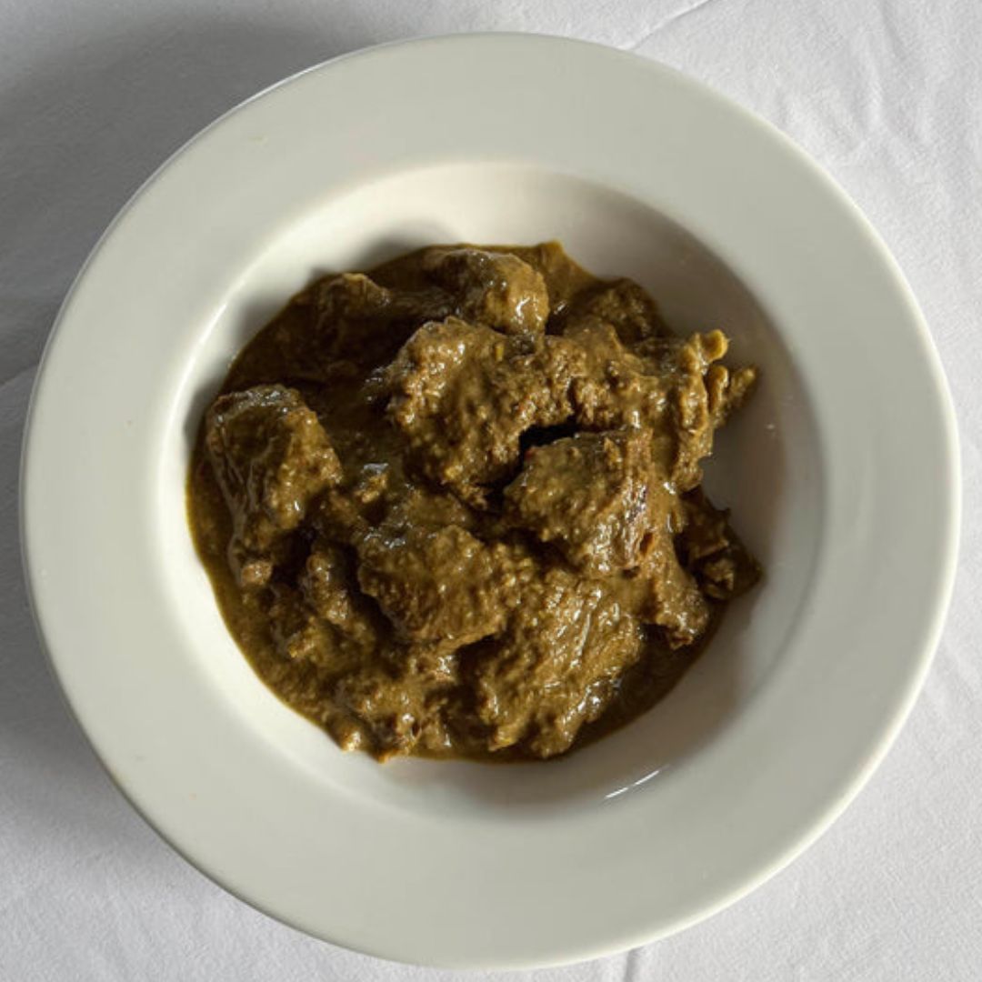 Bowl of Malaysian beef curry with tender beef shin in a rich coconut sauce, served with steamed rice and fresh coriander.