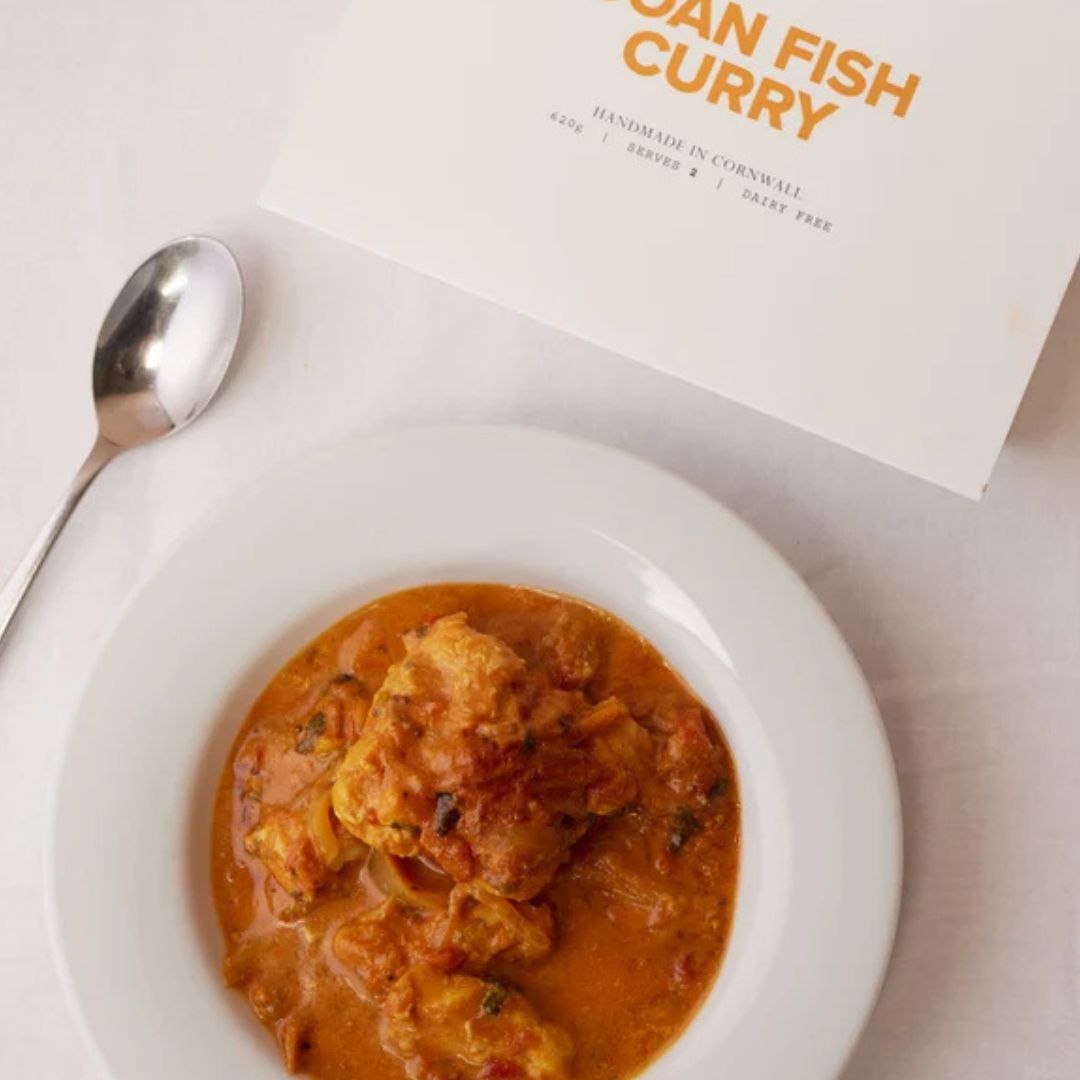Bowl of Goan fish curry with tender hake in a fragrant tomato and coconut sauce, served with steamed rice and coriander.